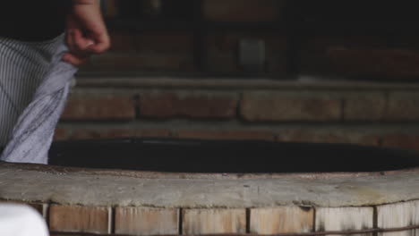 Woman-Holding-Towel-Swirling-The-Towel-Around-The-Traditional-Oven-To-Clean-The-Inside-Wall