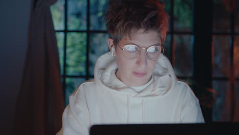 young woman working online on laptop in dark room at night