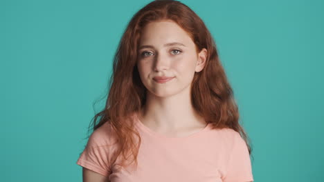 redheaded girl looking at camera on turquoise background.