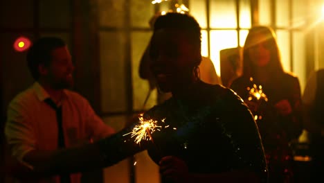 una mujer negra alegre bailando con sparkler.