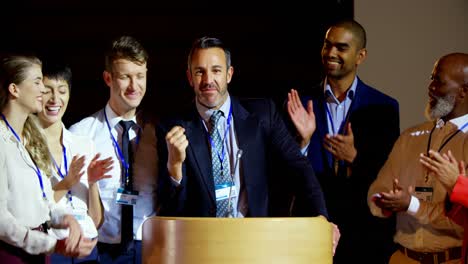 gente de negocios multiétnica feliz aplaudiendo a un hombre de negocios maduro en el escenario en el seminario 4k