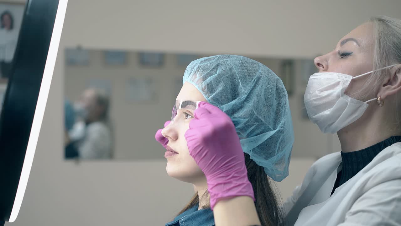 mujer sostiene la regla de la ceja en la cara del cliente para comprobar el tatuaje