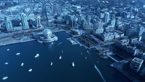 science world false creek olympic village aerial flyover yachts mooring over reflective blue water mirroring iconic modern buildings bords top view overlooking main street connection to downtown east