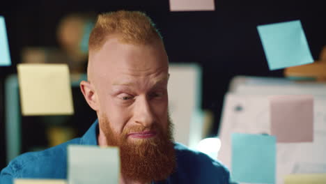 smiling hipster guy looking at stickers with solutions at idea board indoors.