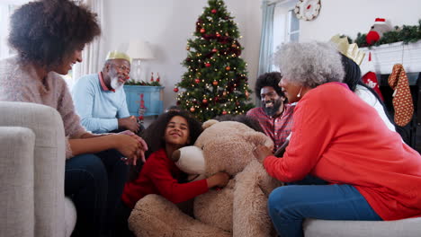 Kinder-Spielen-Mit-Einem-Riesigen-Teddybären,-Während-Eine-Familie-Mit-Mehreren-Generationen-Am-Weihnachtstag-Geschenke-öffnet