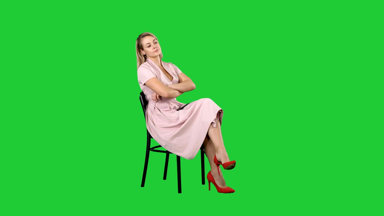 Woman in pink dress sitting on a chair waiting for someone on a Green Screen, Chroma Key