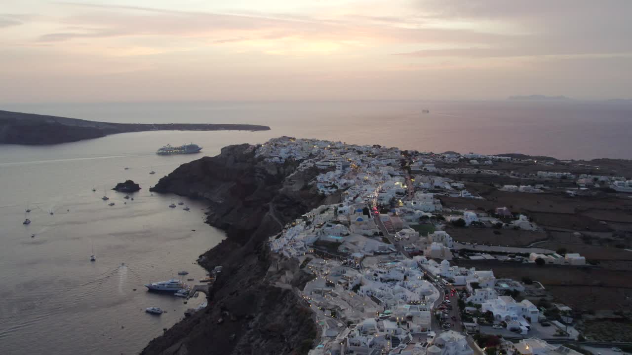 tomada de avión no tripulado de santorini grecia acantilado y casas blancas en el atardecer barcos marina 4k