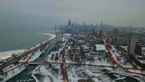 Drone-shot-rising-away-from-the-Lincoln-park,-misty,-winter-evening-in-Chicago,-USA---pull-back,-drone-shot