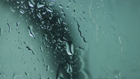 rain striking vertical glass pane, extreme close up in real time