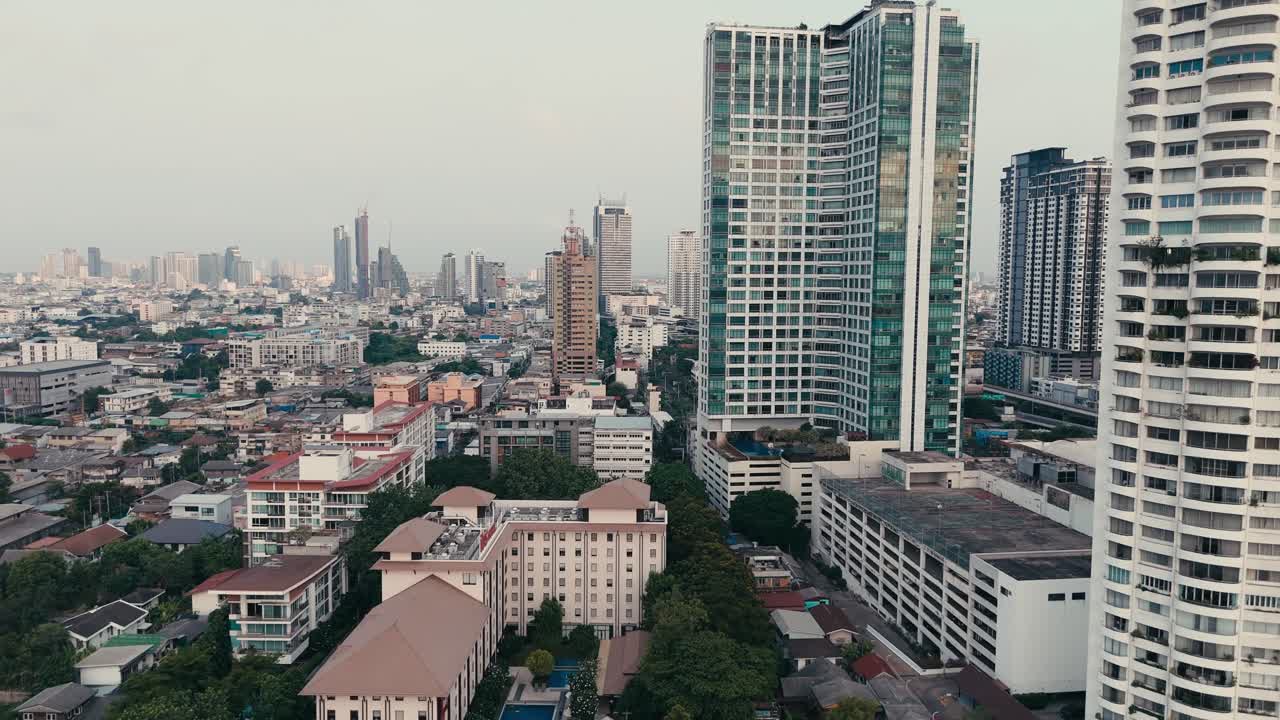 Vista de dron de la ribera de Bangkok mostrando torres frente al río, edificios residenciales, el borde del canal y un denso horizonte urbano con arquitectura moderna y desarrollo de la ciudad.
