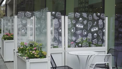 lovely-seating-outside-the-restaurant-with-colorful-flowers-avocados-ice-cream-glass-wall-sunny-bright-day-city-vibe-scenery-no-one-around-moody