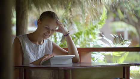 Woman-using-tablet-PC-sitting-outdoor-in-tropics