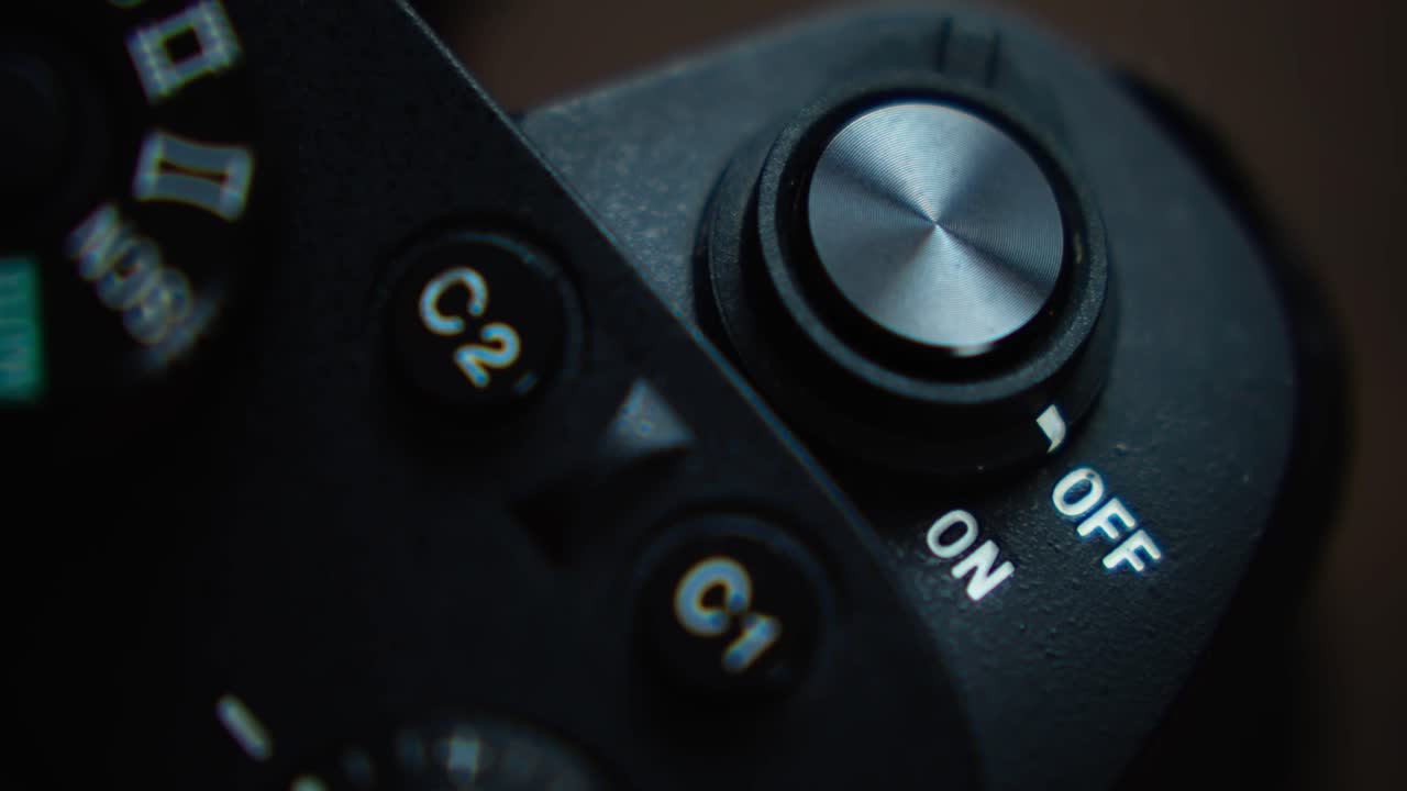 A hand turns on a camera, close shot