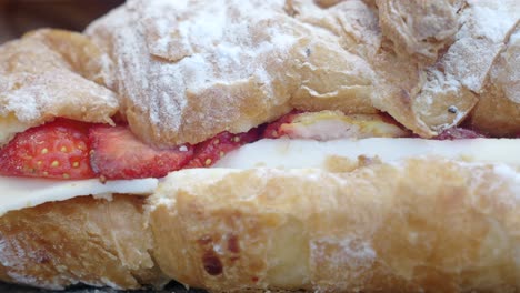 close-up of a croissant with strawberries, cream, and powdered sugar