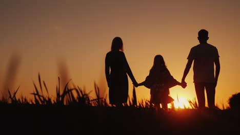 parents with the child stand in a picturesque place, admiring the sunrise. holding hands. happy family concept