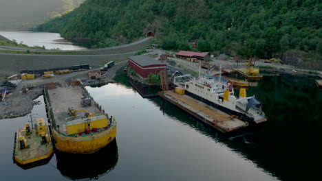 industrial harbour in fjord in rural landscape with ferry and shipping vessels docked at daytime