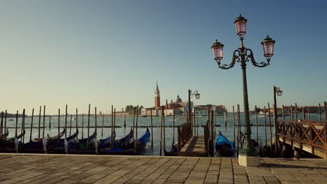 Gondolas,-typical-boats-from-Venice,-moving-on-the-water-in-the-lagoon-near-the-main-square