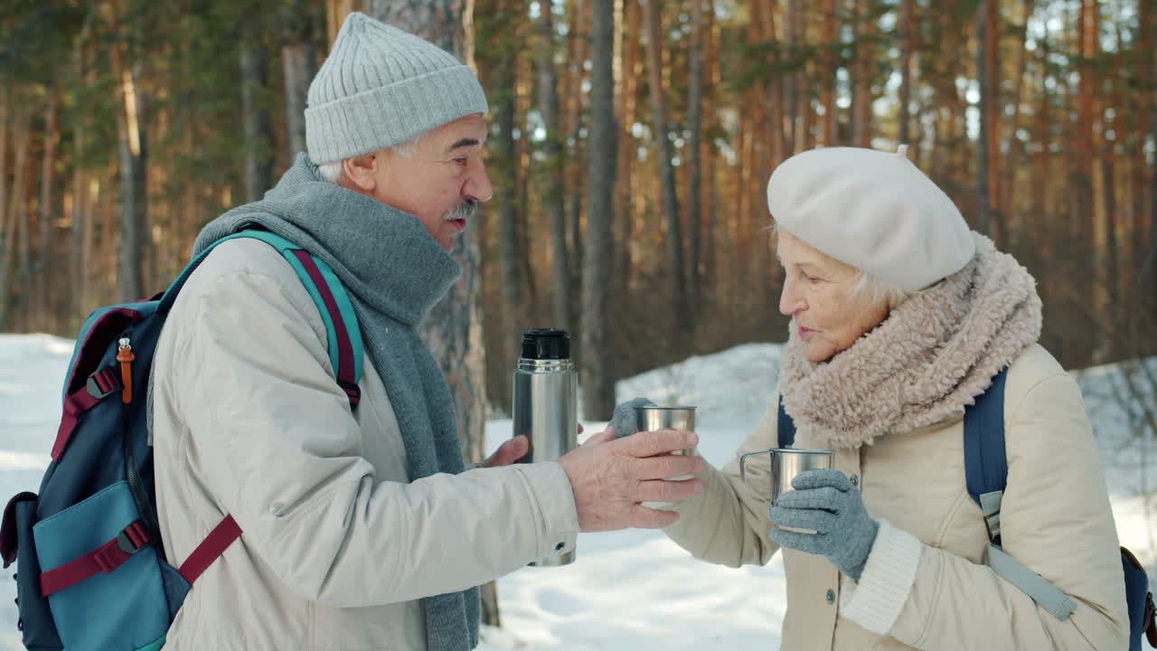 Senior Couple Enjoying Hot Drinks in Winter Forest