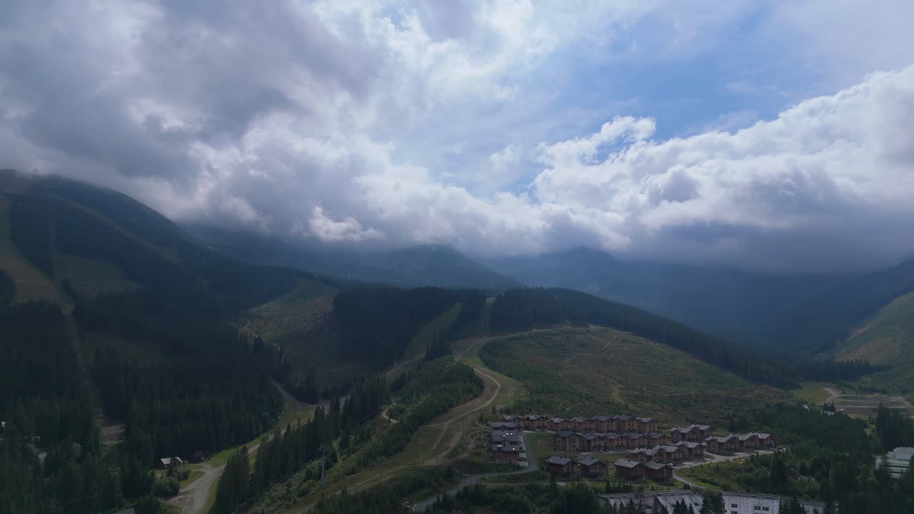 Aerial footage of Demanovska Dolina in Slovakia, showing Jasna ski resort, Vrbicke pleso lake, mountain peaks, and drifting clouds. Beautiful nature and travel visuals from the Zilina region