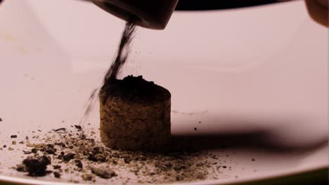 empty plate with a wooden cork in the middle is being used by a pipe smoker to knock out the left over ashes from the tobacco he is hitting it multiple times to empty it thoroughly safe use close up