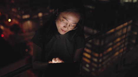 mujer trabajando en una tableta por la noche en un balcón