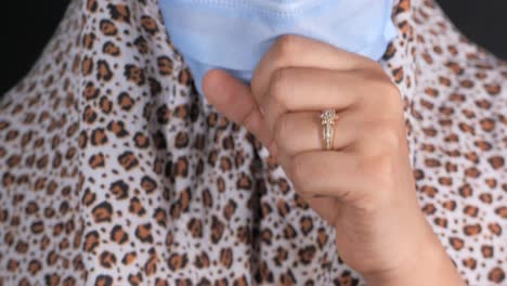 woman wearing a face mask and a leopard print scarf with a ring on her finger