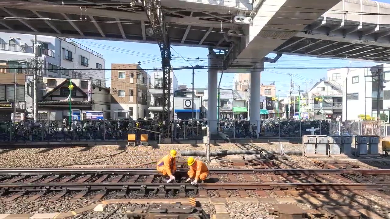 都市の踏切で線路を保守する鉄道作業員