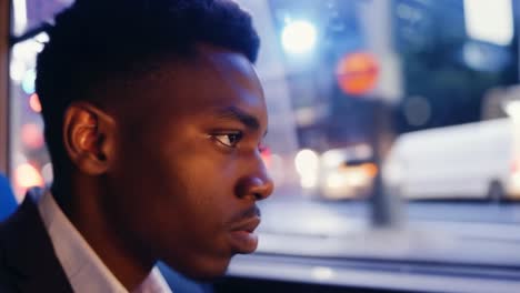 man looking out window on a bus at night