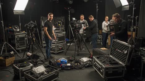 behind the scenes of a video production: crew members organizing equipment and setting up for a filming session with cameras and lighting gear