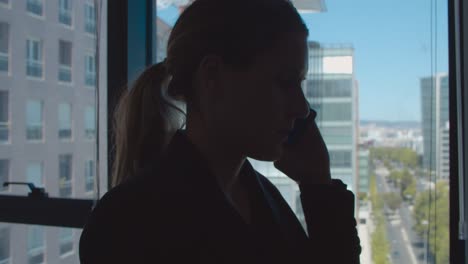 Dark-silhouettes-of-businesswoman-standing-near-window