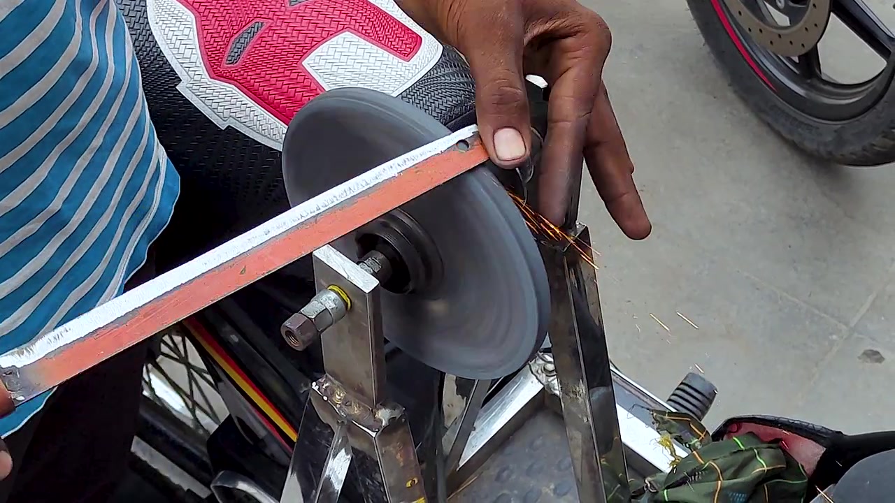 Knife sharpening on rotating grinding wheel creates bright sparks as craftsman works blade edge by hand, showing traditional metalworking, tool repair and workshop craftsmanship.