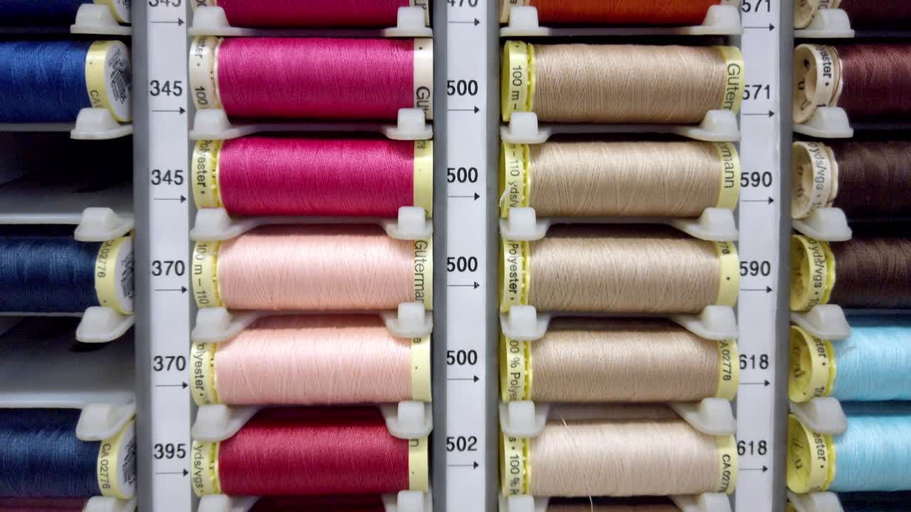 Rows of colorful sewing threads organized by tone inside a professional supply display