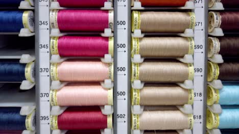 rows of colorful sewing threads organized by tone inside a professional supply display