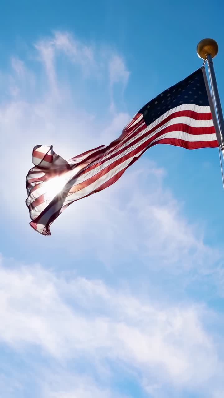 Angolazione verso l'alto di una bandiera americana che sventola contro un cielo blu, ideale per video patriottico.