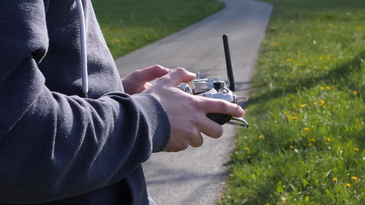 primer plano de las manos de un joven que vuela un dron de carreras fpv en los campos