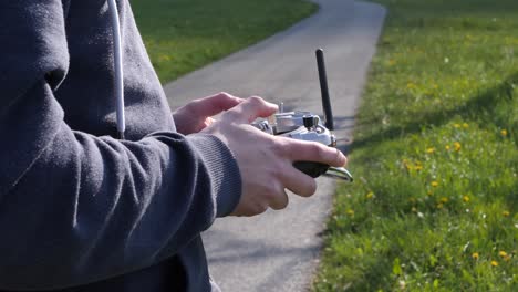 Close-up-hands-of-a-young-man-flying-a-fpv-racing-drone-in-the-fields