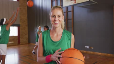 Portrait-of-caucasian-female-basketball-player-with-teammates-in-background