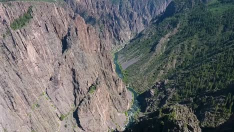 a fly-over drone shot panning down into black canyon, an extreme, steep-walled gorge, containing massive rock spires, carved out by the gunnison river, in gunnison national park, in western colorado