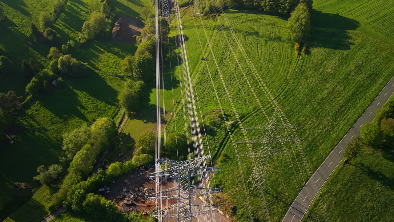 High voltage electricity cables crossing green fields and countryside landscape in Germany