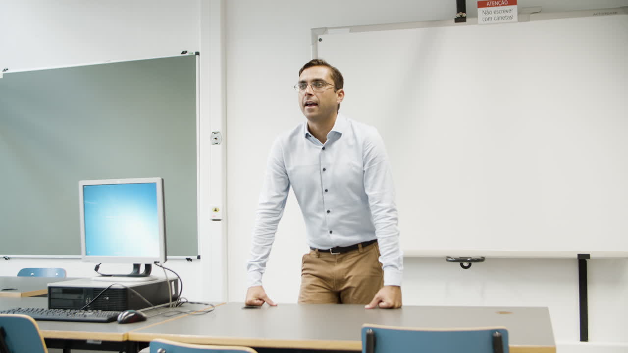 profesor sonriente de pie con las manos en la mesa y hablando con los estudiantes en el laboratorio de computación