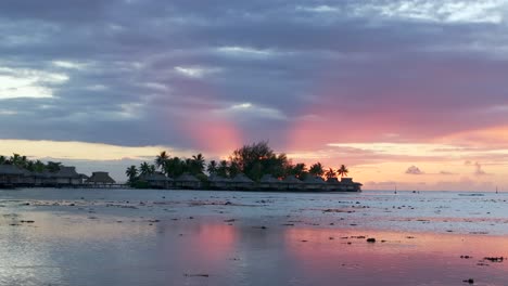 stunning vibrant pink orange sunset sun rays sofitel kia ora resort bungalow villas moorea island french polynesia aerial drone cooks opunohu bay lagoon coral reef pacific ocean slide right motion