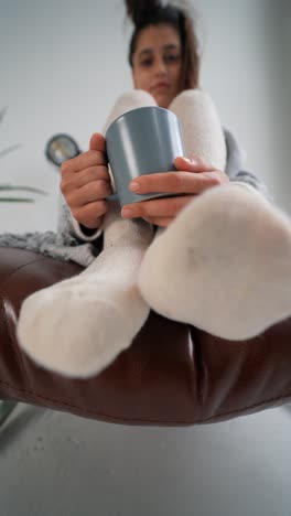 mujer relajándose en un sofá con una taza