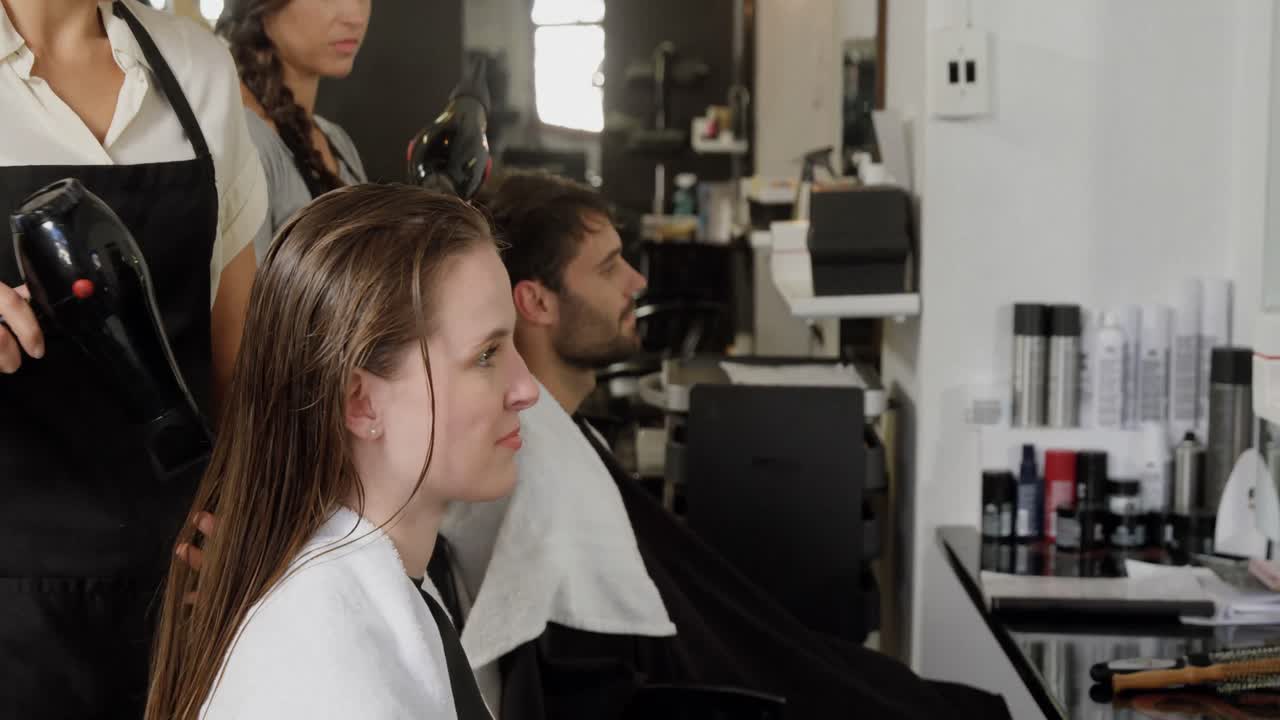 Two hairdresser blow drying their client hair