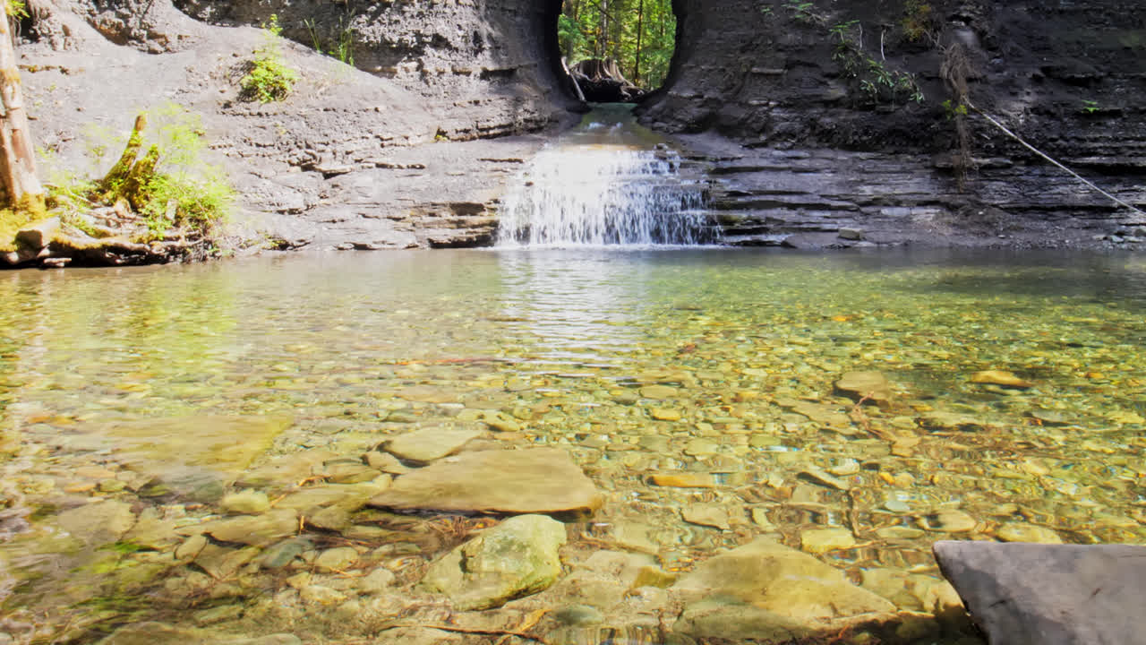 Woman Sitting alone at Lakeside in Forest Watching Rock Hole Waterfall and Relaxing, Peaceful Nature