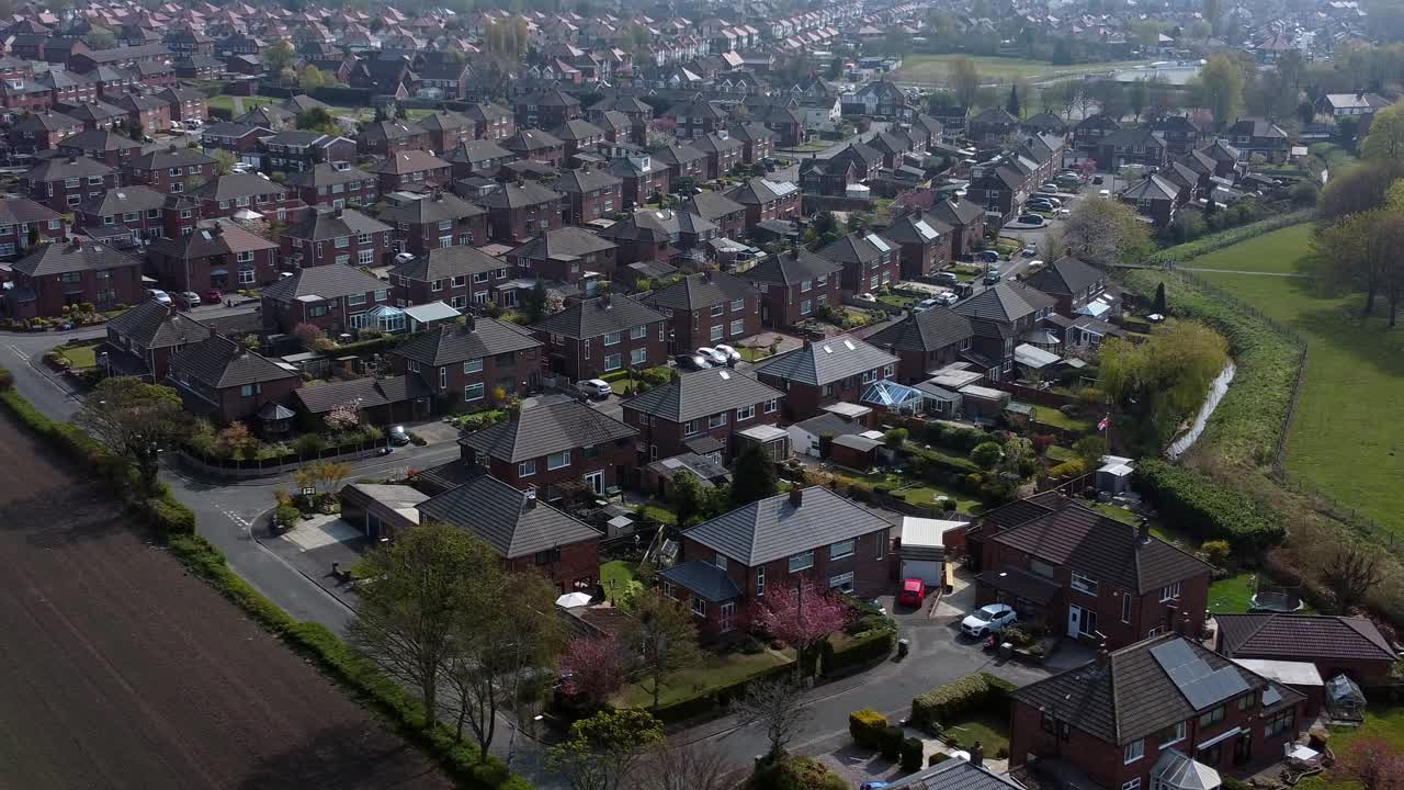 Luftfoto af et boligområde på landet, der flyver over engelske landbrugsarealer med bolighuse, hvor kameraet trækker sig tilbage mod højre.