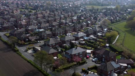 Countryside-housing-estate-aerial-view-flying-above-England-farmland-residential-community-houses-pull-back-right-shot