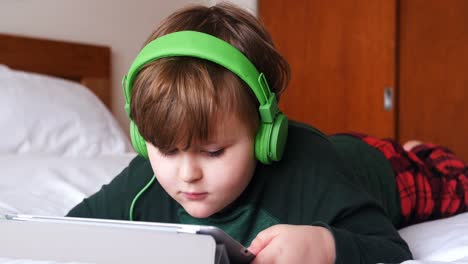 Boy-in-headphones-using-digital-tablet-in-bedroom-4k