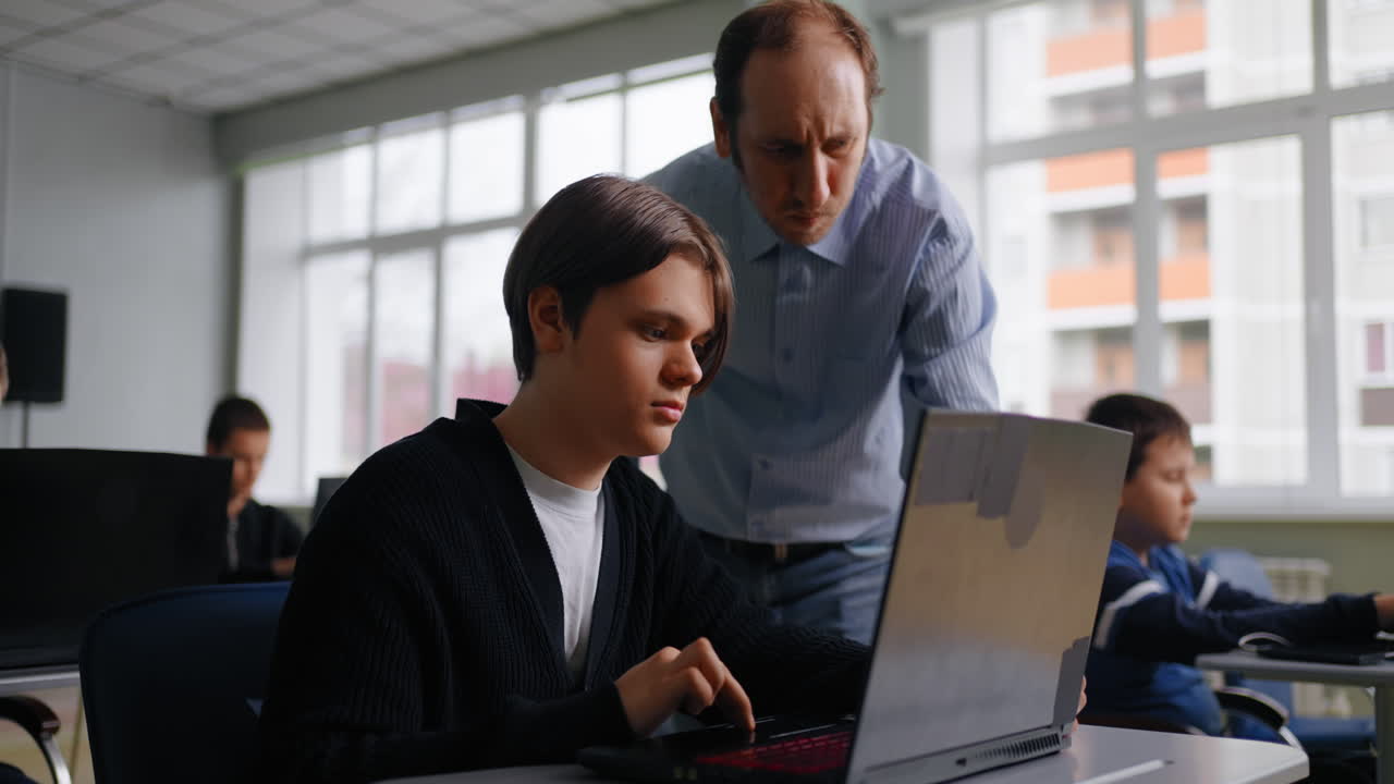 maestro ayudando al estudiante con una computadora portátil en el aula