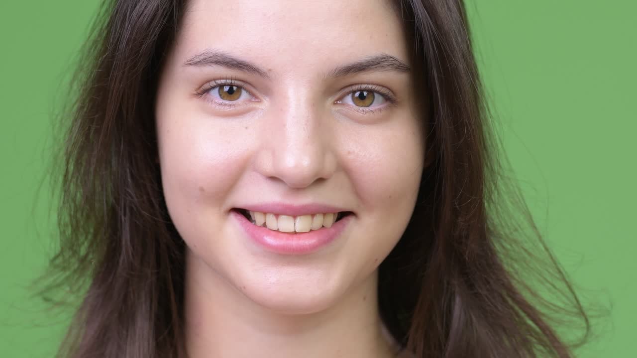 joven feliz mujer hermosa sonriendo contra un fondo verde