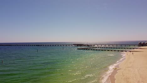 long pier extending into the ocean from a sandy beach